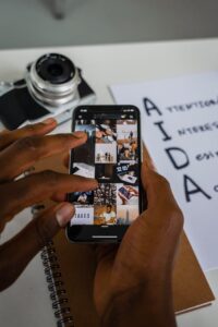 Close-up of hands using a smartphone with a camera and notepad nearby, indoors.